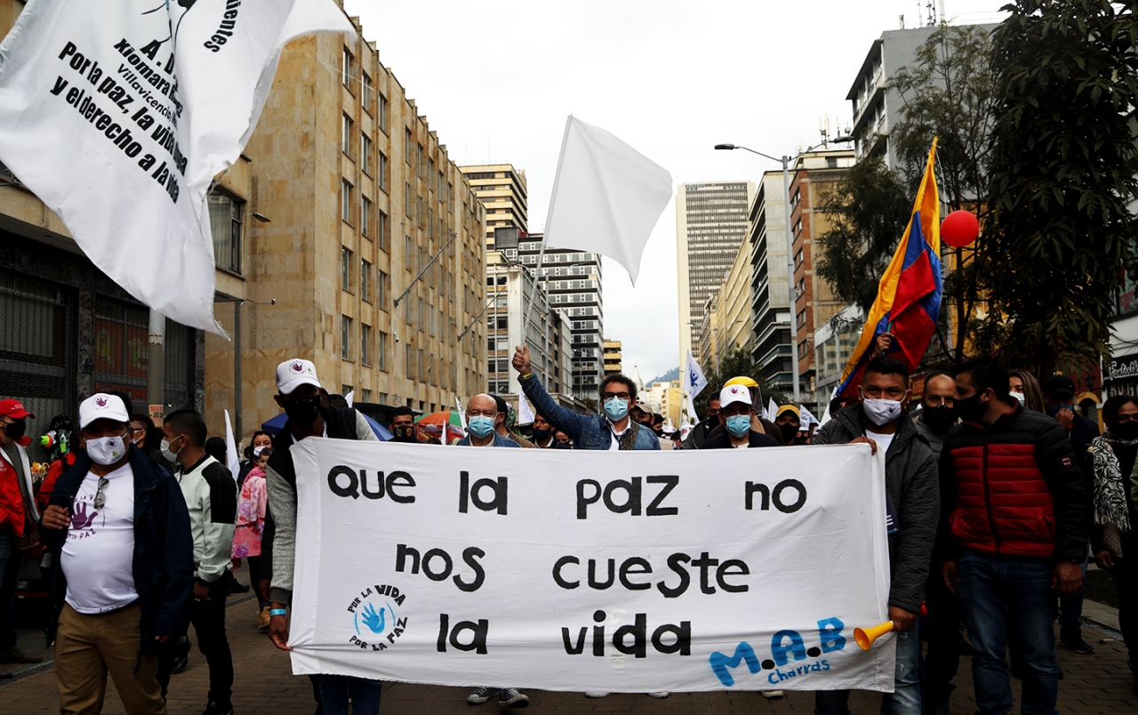 Marcha de las FARC encabezadas por Pastor Alape y por Carlos Lozada|Marcha de las FARC por la Séptima de Bogotá|Fin de la Marchas en la Plaza Simón Bolívar|Imagen de un ex combatiente asesinado en una pancarta de las FARC|Pancarta con la palabra Paz de las FARC|Pancarta 'Somos el grito de los que ya no están'|Performance de un actor y activista en las marchas de las FARC|Retrato en las marchas de las FARC|||