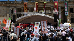 La tarima de los líderes sindicales ubicada delante del Congreso de la República.|Miembros de la Confederación de Trabajadores de Colombia marchan|Directores de varios sindicatos y organizaciones laborales en el acto central en la Plaza de Bolívar|Campaña "Nico vive"|Miembros de la Confederación General del Trabajo durante la marcha del 1 de Mayo|Miembro de Partido Comunista marcha en frente de efectivos de la Policía|Los manifestantes recorriendo la carrera Séptima para llegar a la Plaza de Bolívar.|Estudiantes de la Universidad Cooperativa de Colombia marchan|Algunos manifestantes también se pronunciaban sobre el asesinato de líderes sociales en el país|Miembros del sindicato Memoria Viva en su entrada a la plaza para la reunión de todos los manifestantes|Una de las representaciones simbólicas de la paz en la carrera Séptima y debajo la bandera de la Unión Patriótica.|Manifestantes frente a la Catedral Primada con una bandera de la causa comunista|Los bailes típicos y la música robaron la atención del público dentro de la marcha|El Presidente de la asociación de las familias de las víctimas de la sociedad civil de soldados, policías y guardias de Colombia atiende la protesta|Los tambores se sumaron a las voces de denuncia dentro de la Plaza de Bolívar|||